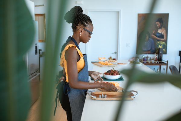 An adult woman preparing fresh ingredients on a chopping board in her home kitchen.